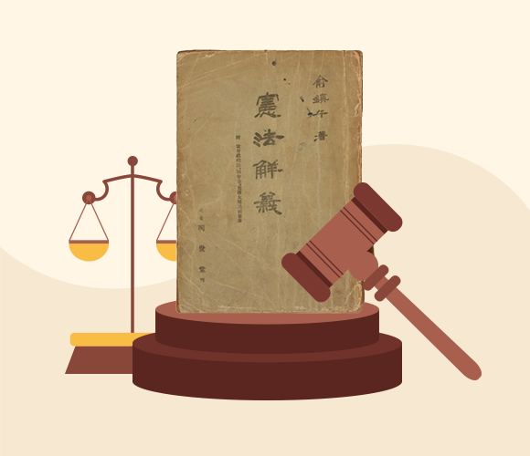 베이지색 배경이다. 중앙에 ‘헌법해의’ 책이 세워져 있고, 그 왼쪽에는 법의 공정함을 상징하는 저울이 있다. 오른쪽에는 목재 판사봉이 받침대 위에 올려져 있다.