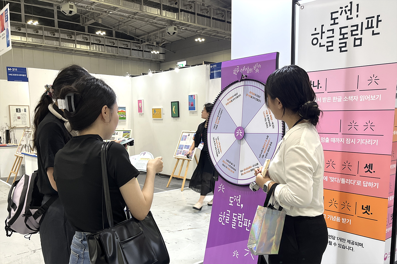 ‘도전! 한글 돌림판’ 현장 사진이다. 보라색 한글 돌림판 앞에서 관람객이 체험하고 있다.