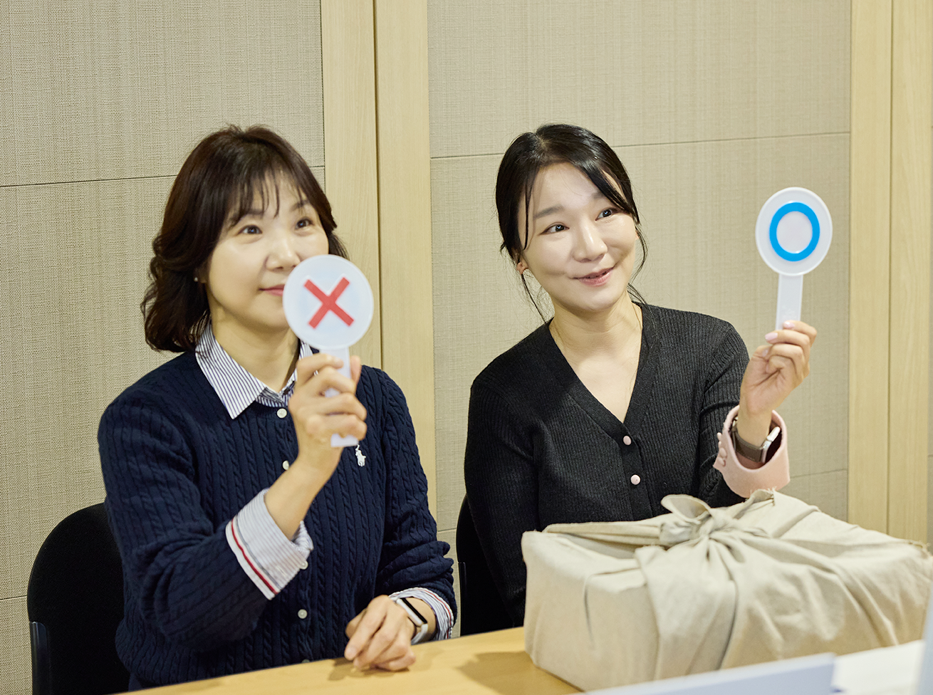 초등학교 연계 원격 및 현장 교육 사진이다. 두 명의 강사가 OX 표시판을 들고 웃으며 수업을 이끌고 있다. 
