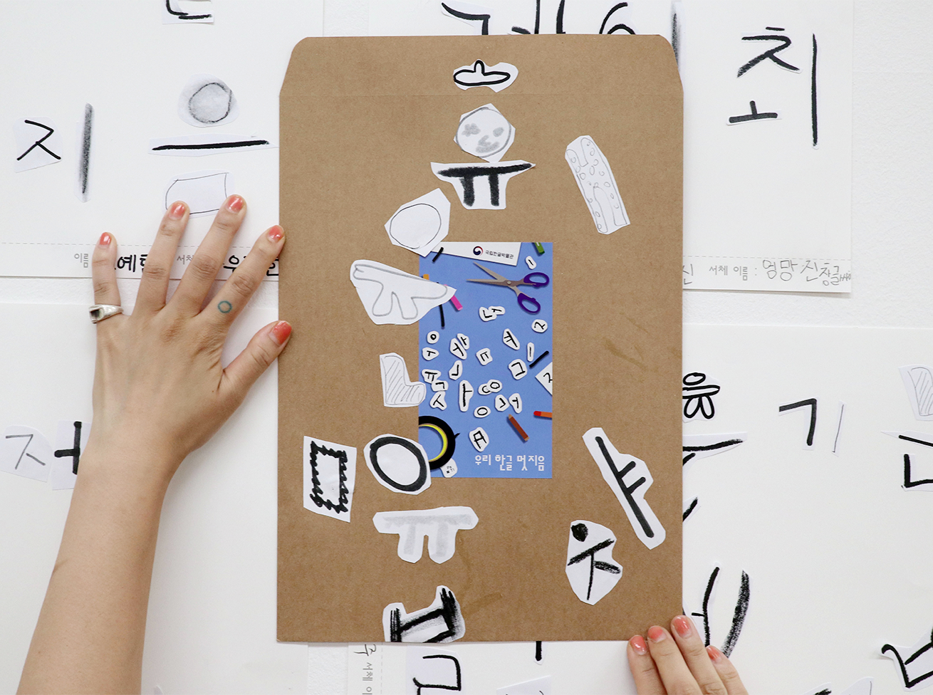 ‘우리 한글 멋지음’ 교육 현장 사진이다. 종이 위에 잘라낸 한글 조각들을 붙여 꾸민 작품이 있다.