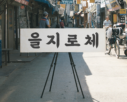 배달의민족에서 제작한 글꼴 ‘을지로체’ 사진이다. 좁은 골목길에 세워진 입간판에 굵고 단정한 글씨로 ‘을지로체’라고 쓰여 있다.