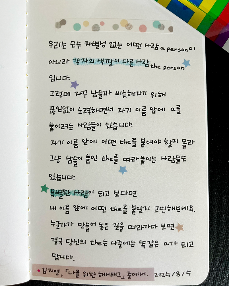 8월호 한 글 쓰기 참여작 사진이다. 노트에 펜으로 김지영의 ‘나를 위한 해시태그’를 필사했다. ‘우리는 모두 차별성 없는 어떤 사람(a person)이 아니라 각자의 색깔이 다른 사람(the person)입니다. 그런데 자꾸 남들과 비슷해지기 위해 끊임없이 노력하면서 자기 이름 앞에 a를 붙이려는 사람들이 있습니다. 자기 이름 앞에 어떤 ’the‘를 붙여야 할지 몰라 그냥 남들이 붙인 ’the’를 따라붙이는 사람들도 있습니다. 특별한 사람이 되고 싶다면, 내 이름 앞에 어떤 ‘the’를 붙일지 고민해 보세요. 누군가가 만들어 놓은 길을 따라가다 보면 결국 당신의 ‘the’sms 나중에는 똑같은 ‘a’가 되고 맙니다.