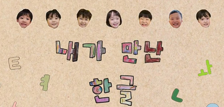 ‘2025년 내가 만난 한글 사진‧영상 공모’ 영상 분야 대상 수상작 ‘가장 아름다운 한글’ 사진이다. 연한 갈색 도화지 같은 배경 위에 ‘내가 만난 한글’이라는 글씨가 크고 알록달록하게 손으로 그린 듯 표현되어 있으며, 글자 주변에는 ‘ㅌ’와 ‘ㄹ’ 등 한글 자모 모양이 연필로 그려져 있다. 화면 윗부분에는 일곱 명의 아이 얼굴 사진이 동그랗게 오려 붙인 듯 줄지어 배치되어 있고, 각각 웃거나 미소 짓는 표정으로 화면을 바라보고 있다.