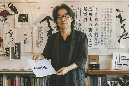강병인 작가가 ‘마뗑킴’ 한글 로고가 적힌 종이를 들고 미소 짓고 있다.