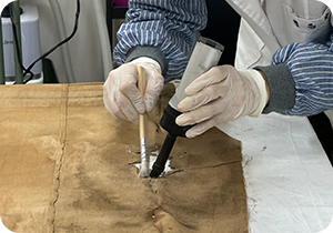 한 사람이 흰 장갑을 낀 채로 오래된 갈색 천 소재의 ‘덕온공주가 방장’ 건식 세척 작업을 진행하고 있다.