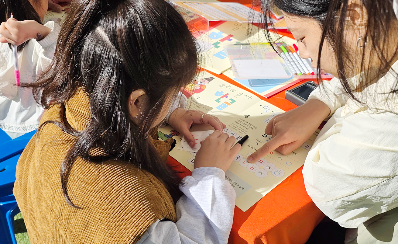 ‘찾아가는 사투리 이야기 콘서트’ 연계 체험 활동 사진이다. 아이가 보호자와 함께 종이에 글을 쓰고 있다.