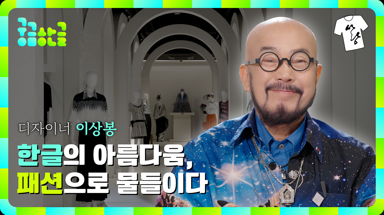 ‘궁금한글’ 이상봉 디자이너 유튜브 썸네일 사진이다. 배경은 하얀색 전시 공간이며, 마네킹이 한글 문양의 옷을 입고 있다. 오른쪽에는 안경을 쓰고 파란 스카프를 한 이상봉 디자이너의 사진이 있다. 왼쪽 하단에는 ‘한글의 아름다움, 패션으로 물들이다’라고 적혀있다.