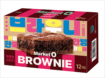 오리온의 ‘마켓오 브라우니 한글’ 사진이다. 짙은 갈색과 분홍색, 살구색 줄무늬 배경 위에 실제 브라우니 조각이 크게 인쇄되어 있으며, 주변에 ‘브라우니’, ‘어서와 한국’, ‘안녕’, ‘환영해’ 와 같은 우리말이 적혀있다.