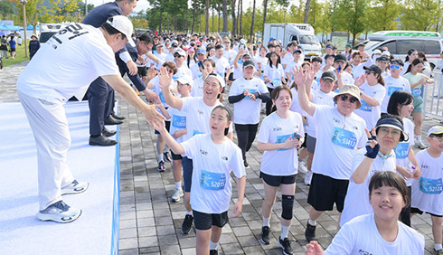 ‘2025 한글런’ 사진이다. 흰색 반팔을 입은 ‘한글런’ 마라톤 참가자들이 카메라를 보고 활짝 웃고 있다.