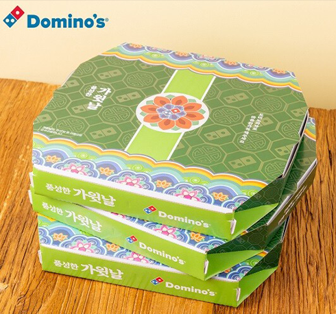 한글날 기념 도미노에서 제작한 ‘가윗날’ 피자 박스 사진이다. 초록색 바탕의 피자 상자에 한국 전통 문양이 새겨져 있고, ‘가윗날’이라고 적혀 있다.
