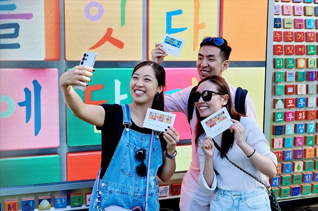 미국 주요 대학을 돌아다니며 한글을 홍보한 ‘한글 트럭’ 사진이다. 한글 자음과 모음이 형형색색으로 꾸며진 대형 한글 트럭 앞에서 세 명의 남녀가 기념 엽서를 들고 자신들의 사진을 찍고 있다.