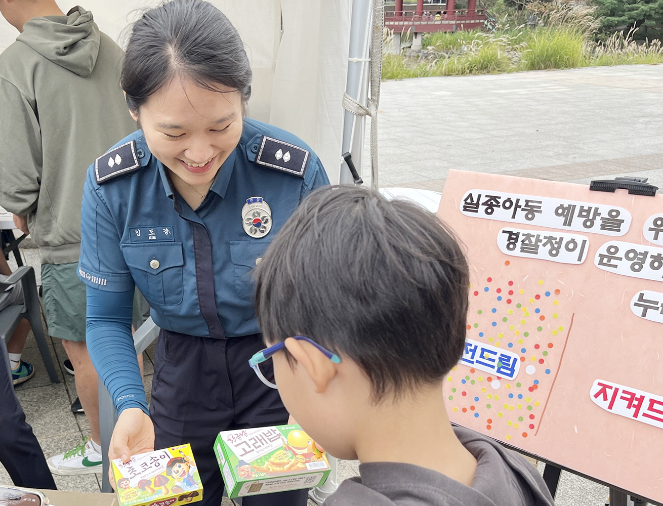 ‘2025 국립한글박물관 한글날 행사’ 현장 사진이다. 경찰 제복을 입은 여성이 어린이에게 오리온 고래밥과 초코송이를 건네는 모습이다.