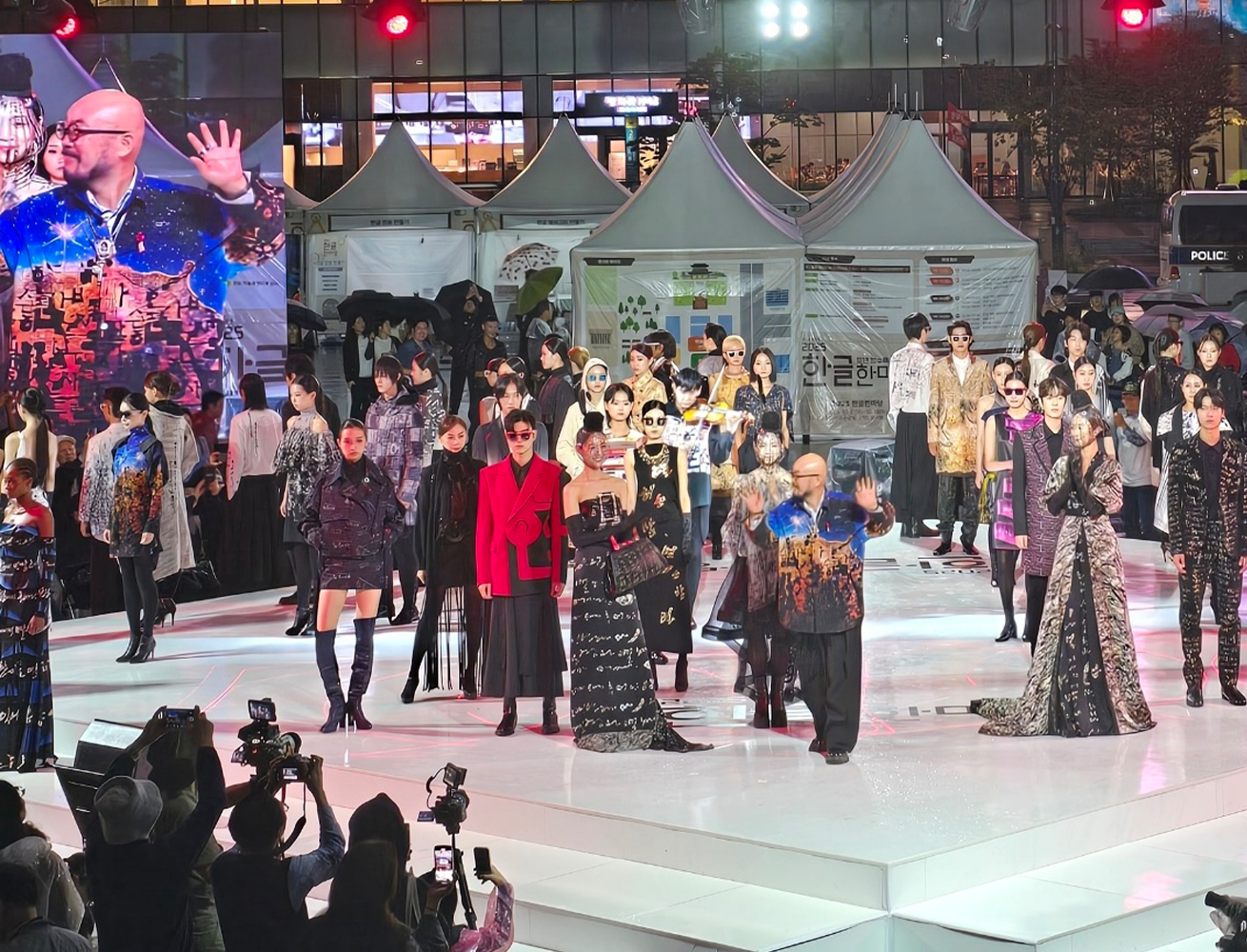 ‘2025 한글문화산업전’ 행사 현장 사진이다. ‘한글 패션쇼’에 참가한 모델과 이상봉 디자이너가 무대 위에서 인사를 하고 있다.
