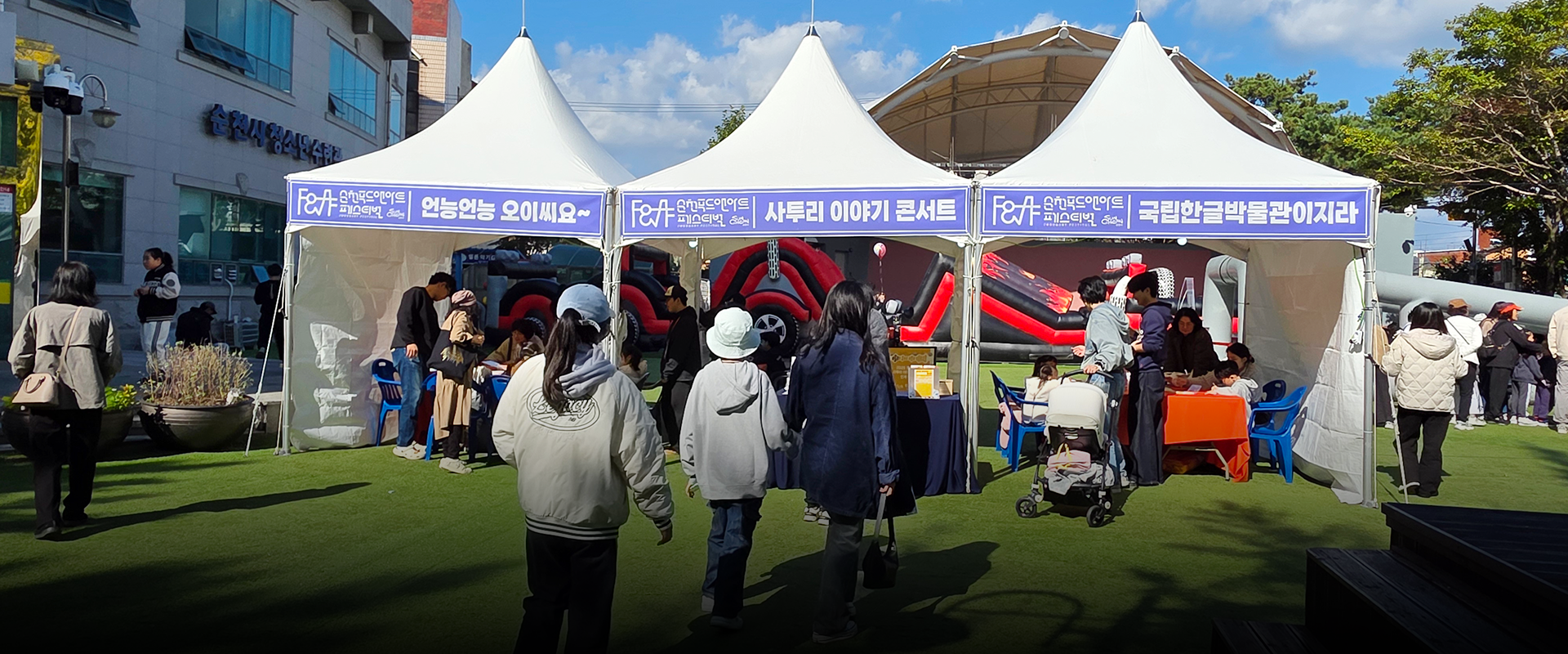 기획 기사 사진. 순천에서 열린 ‘찾아가는 사투리 이야기 콘서트’ 현장 사진이다. 흰색 천막 세 개가 나란히 서 있고, 각 천막의 현수막에는 흰 글씨로 각각 ‘언능언능 오이씨요~’, ‘사투리 이야기 콘서트’, ‘국립한글박물관이지라’라고 적혀있다. 천막 주변에는 체험하러 온 관광객들이 모여 있다. 그 아래에는 기사의 제목 ‘전남 순천에서 열린 찾아가는 사투리 이야기 콘서트’가 쓰여있다.
