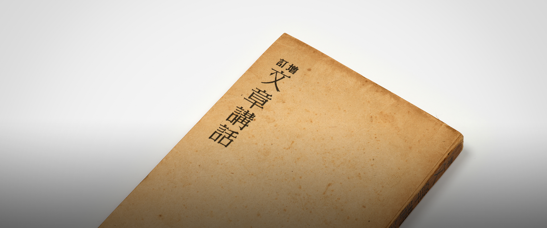 소장품 이야기. 흰색 배경에 이태준의 ‘문장강화’ 소장품이 놓여있다. 책 표지는 연한 갈색빛을 띠며 세월의 흔적이 느껴진다. 표지 왼쪽 위에는 ‘문장강화’가 한자로 쓰여있다. 왼쪽 하단에는 하늘색 박스 안에 ‘소장품 이야기’ 문구가 적혀있다. 그 아래에는 기사의 제목 ‘글쓰기의 믿을 구석 이태준, 『문장강화』(1947)’가 쓰여있다.