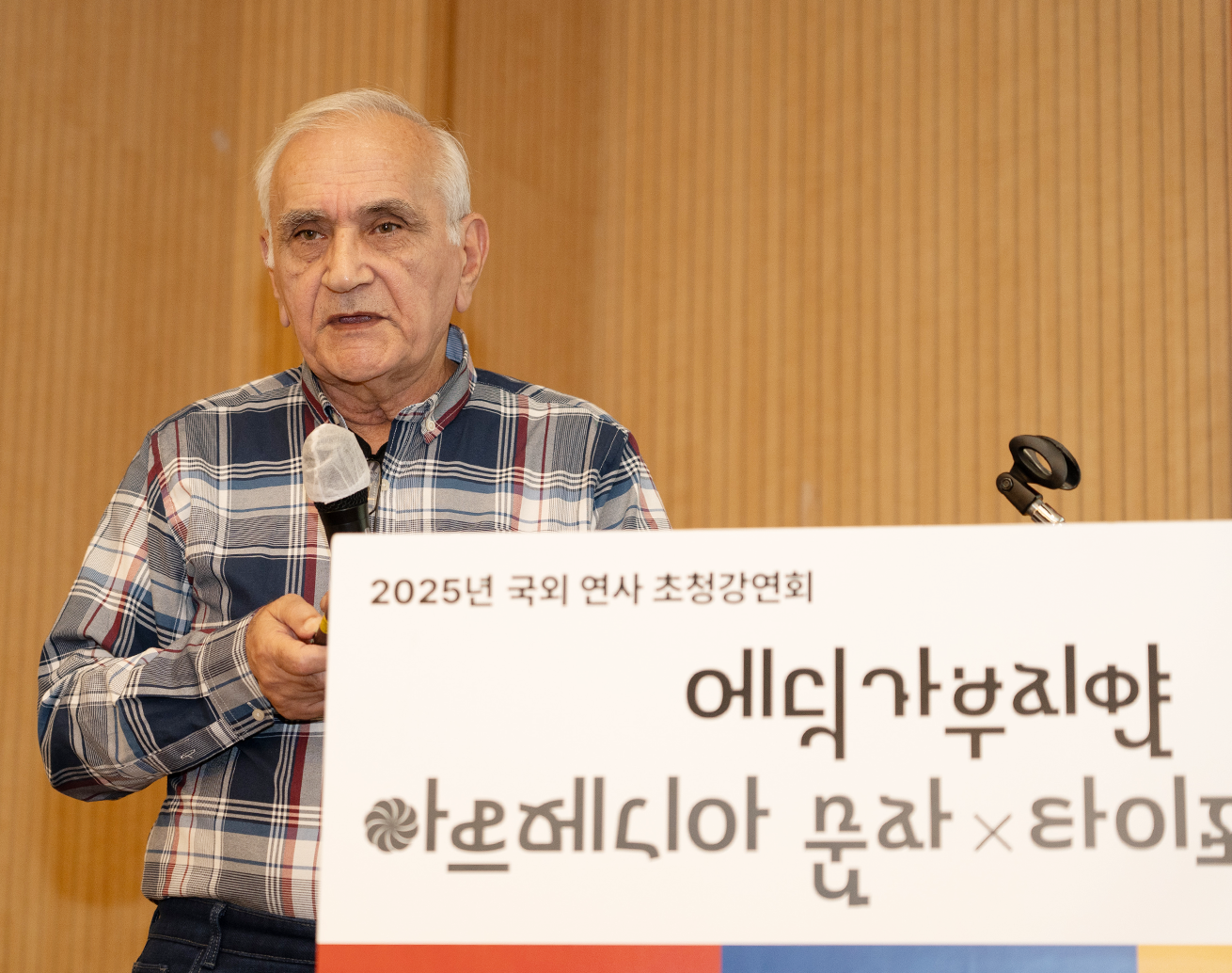 강연자 에딕 가부지안 사진이다. 그는 회색 체크무늬 셔츠를 입고 있으며, 마이크를 들고 강연 중이다.