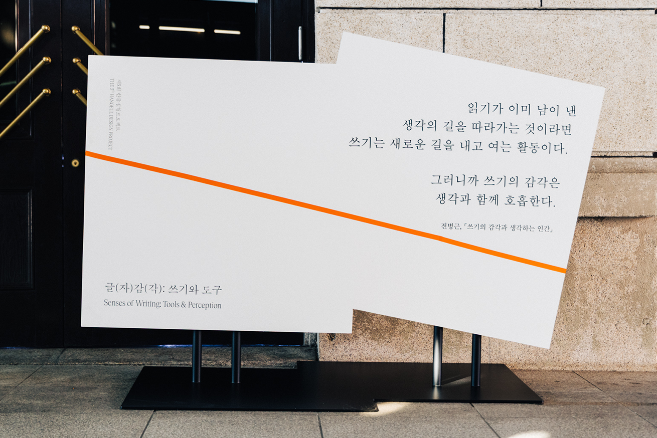 전시장으로 관람객들을 유도하는 문장이 적혀있는 구조물 사진이다. 전병근 작가의 ‘쓰기의 감각과 생각하는 인간’에서 발췌한 문장이 적혀있다. ‘읽기가 이미 남이 낸 생각의 길을 따라가는 것이라면 쓰기는 새로운 길을 내고 여는 활동이다. 그러니까 쓰기의 감각은 생각과 함께 호흡한다.’