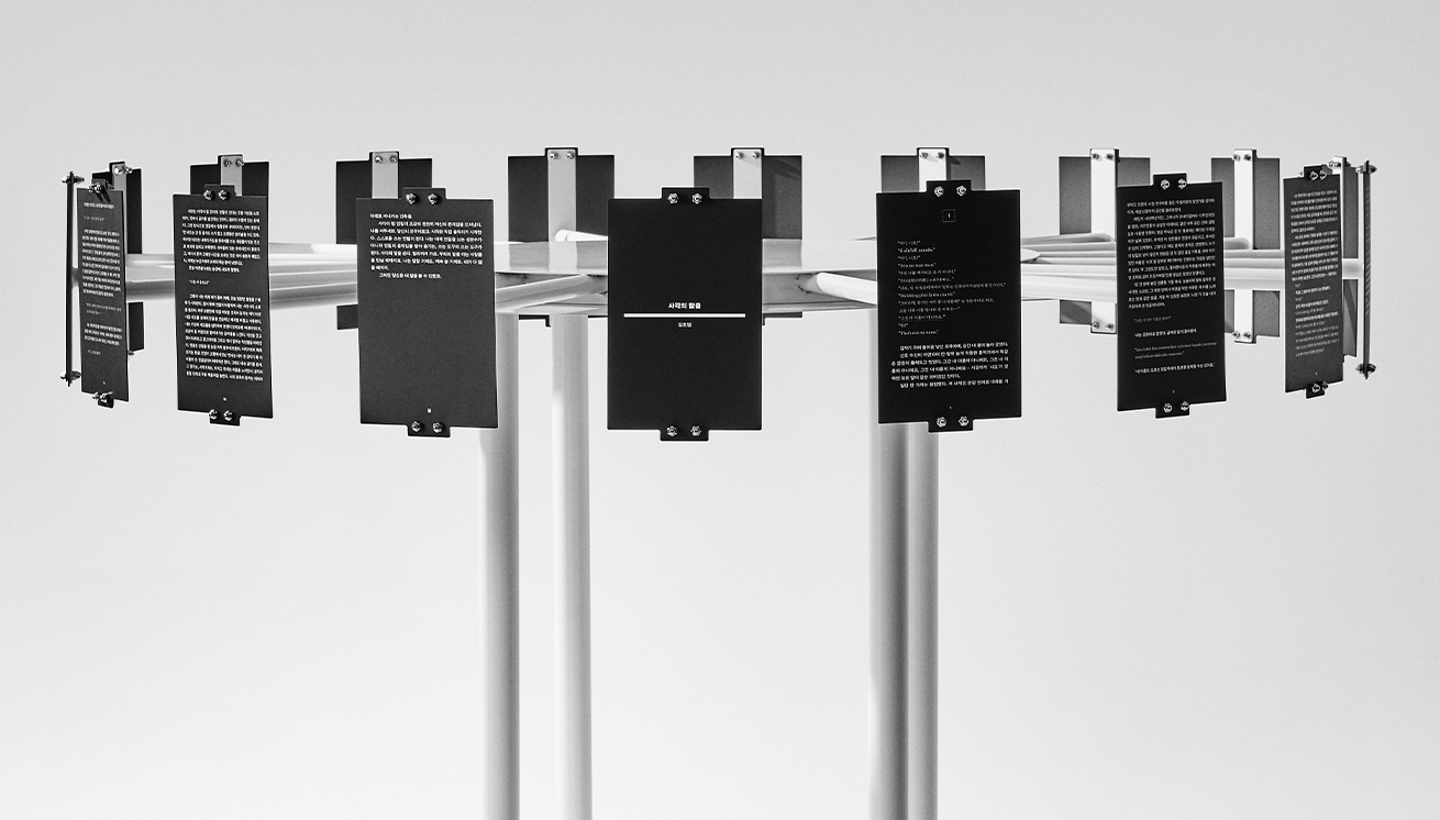 김초엽 작가의 ‘사각의 탈출’ 작품 사진이다. 검은 배경의 카드들이 원형 구조물에 매달려 공간을 둘러싸듯 전시되어 있다.