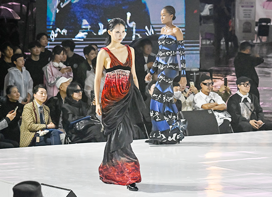 ‘2025 한글한마당(한글문화산업전)’에서 한글이 새겨진 원피스를 입은 모델 두 명이 런웨이를 걷고 있다. 