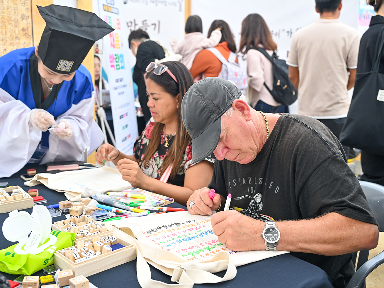 2025년 세종대왕 나신 날 행사 사진이다. 여러 명의 사람이 테이블에 둘러앉아 언해본 따라쓰기를 하고 있다.