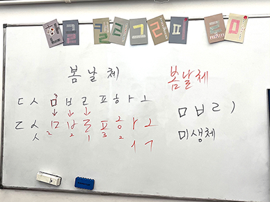 칠판에 ‘봄날체’ 손 글씨를 작성하는 법이 적혀있다.