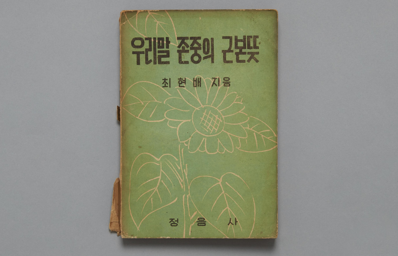 『우리말 존중의 근본뜻』 책 표지 사진이다. 초록색 바탕에 흰색으로 꽃과 나뭇잎이 그려져 있다. 
