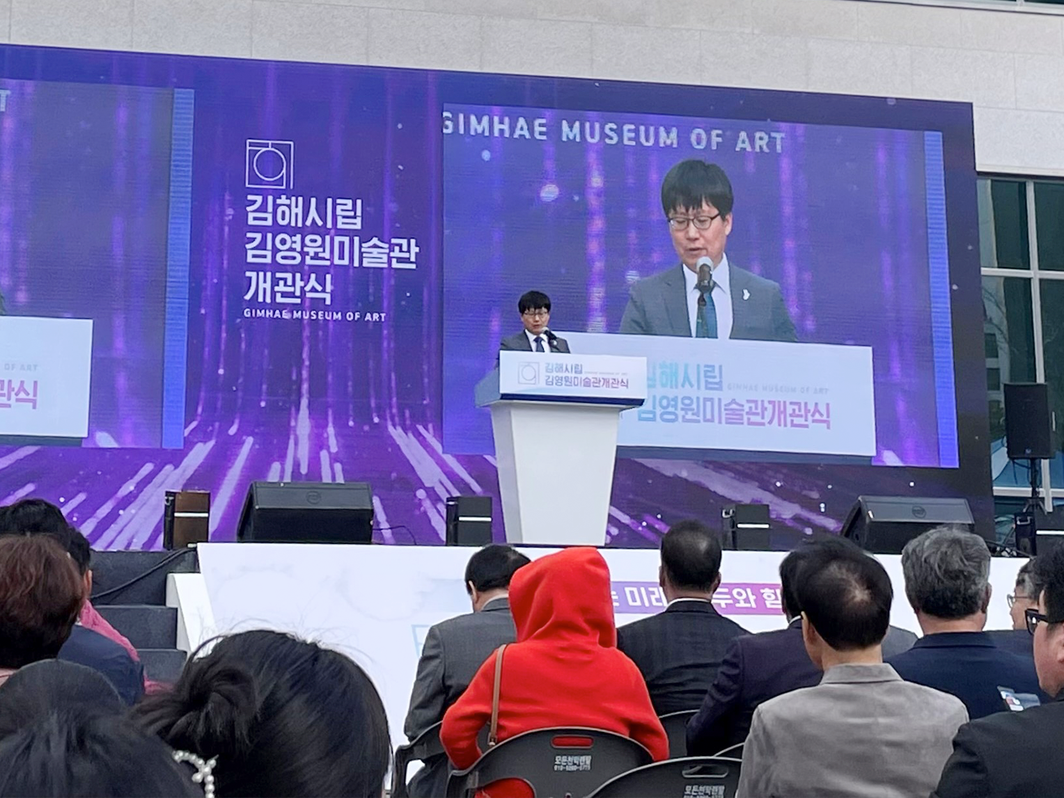김해시립김영원미술관 개관식 현장이다. 연사가 연단에 서서 축사를 발표하고 있다.