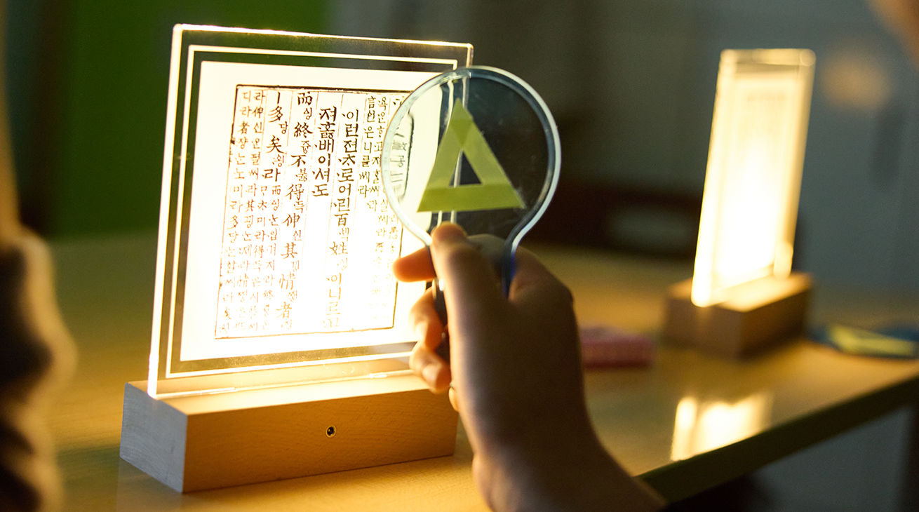 ｢세종의 친구, 한글 지킴이｣ 교구재 사진이다. 빛이 나는 한글 교재를 확대경으로 들여다보고 있다.