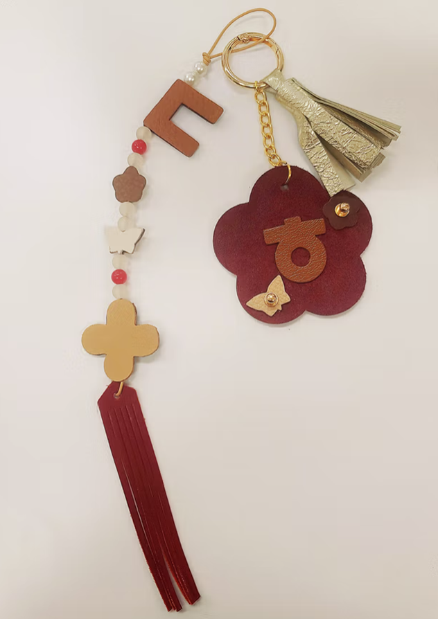 「한글 디자인 공방」 결과물 사진이다. 붉은 꽃장식과 한글 자음으로 장식한 열쇠고리 사진이다.