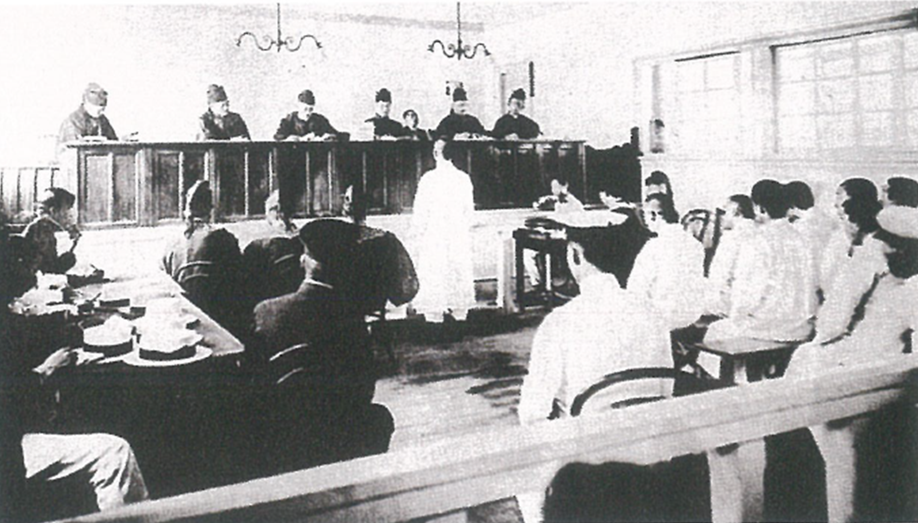 일제강점기 경성지방법원에서의 조선인 재판 광경이다. 앞쪽에는 판사들이 높은 단상에 앉아 재판을 진행하고 있고, 중앙에는 피고로 보이는 인물이 서 있으며 주변에 여러 사람이 앉아 있다.