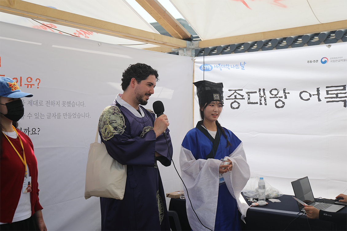 2026년 ‘제629돌 세종대왕 나신 날’ 기념행사 사진이다. 한복을 입은 외국인이 마이크를 들고 ‘세종대왕 어록 따라 읽기’ 체험에 참여하고 있다.