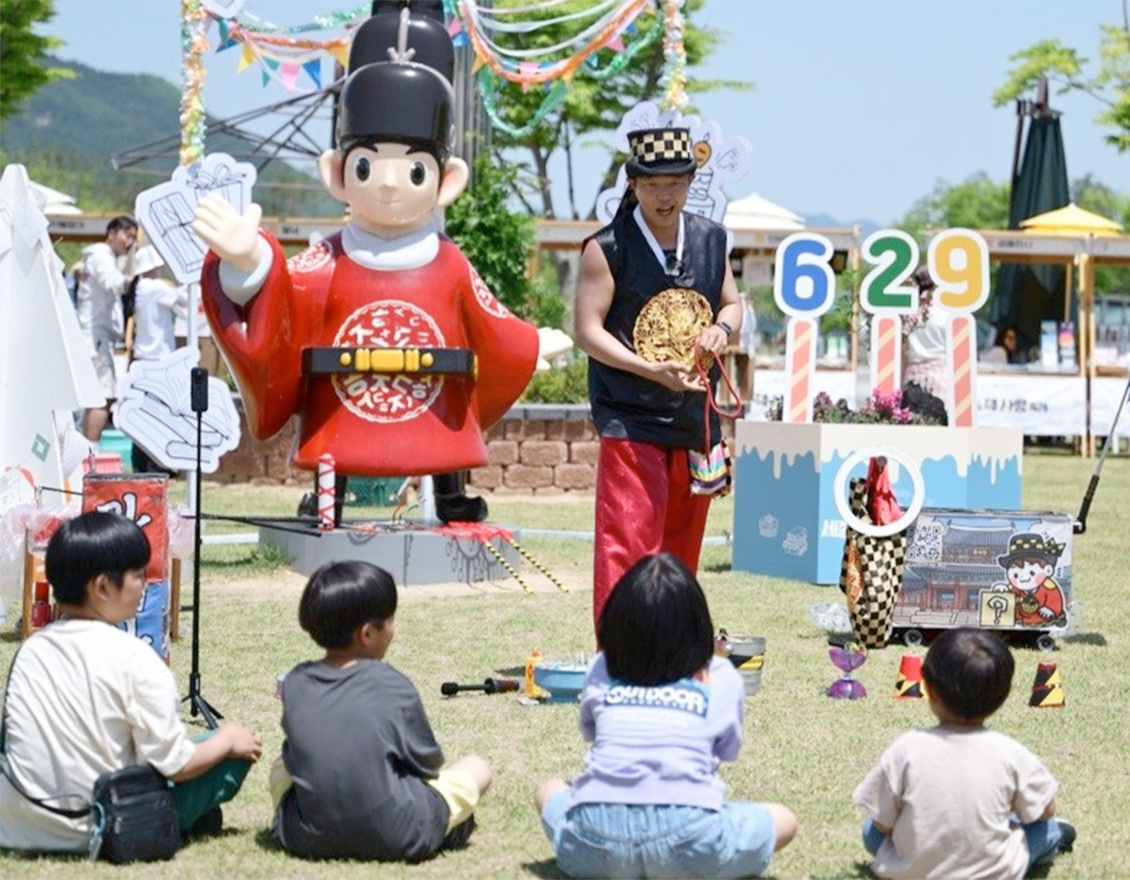 ‘2026 세종 책사랑 축제’ 현장 모습이다. 세종대왕 복장을 한 대형 캐릭터 조형물 앞에 어린이들이 앉아 공연을 관람하고 있다.