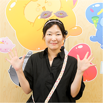검은색 블라우스를 입고 마이크를 찬 배정은 교육 강사가 카메라를 보며 환하게 웃고 있다.
