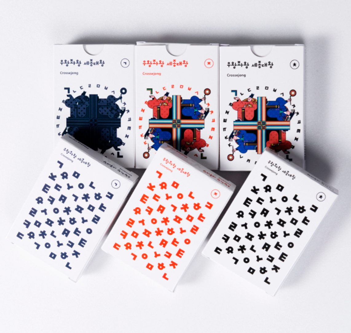 한글 자음과 모음이 인쇄된 카드와 ‘우왕좌왕 세종대왕’ 보드게임 상자 여러 개가 흰색 바닥 위에 펼쳐져 있다.