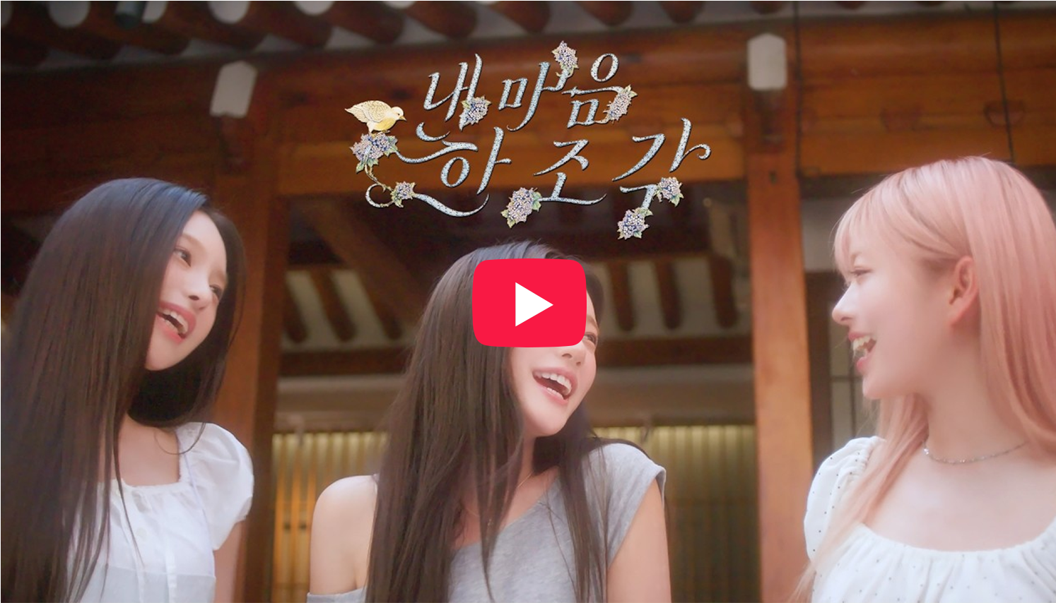 앳하트 ‘내 마음 한 조각’ 뮤직비디오 미리보기 이미지로, 앳하트 멤버 세 명이 서로를 바라보며 웃고 있다. 상단에는 ‘내 마음 한 조각’ 노래 제목이 손 글씨 형태로 표현되어 있다.