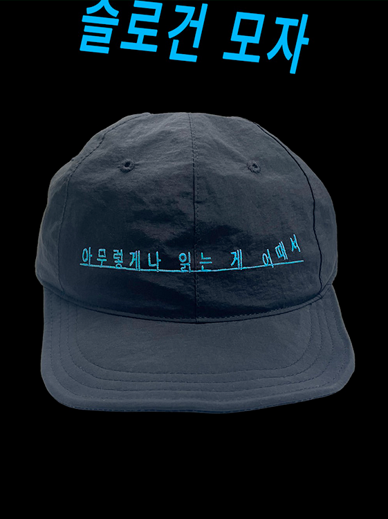 ‘안전가옥’ 모자 이미지다. 짙은 색 모자 앞면에 청록색 글씨로 ‘아무렇게나 읽는 거 어때’라는 문구가 자수로 새겨져 있으며, 이미지 상단에는 ‘슬로건 모자’라는 문구가 적혀있다.