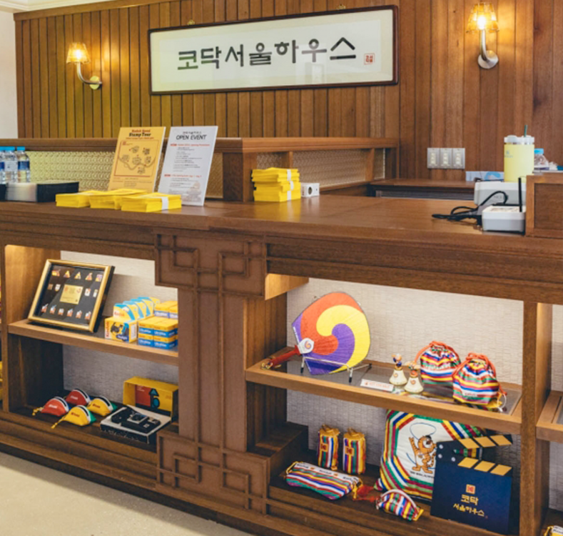 코닥서울하우스 내부 이미지다. 목재 진열대 위에 전통 문양과 색상을 활용한 소품과 굿즈가 전시되어 있으며, 상단에는 ‘코닥서울하우스’라는 간판이 걸려 있다.