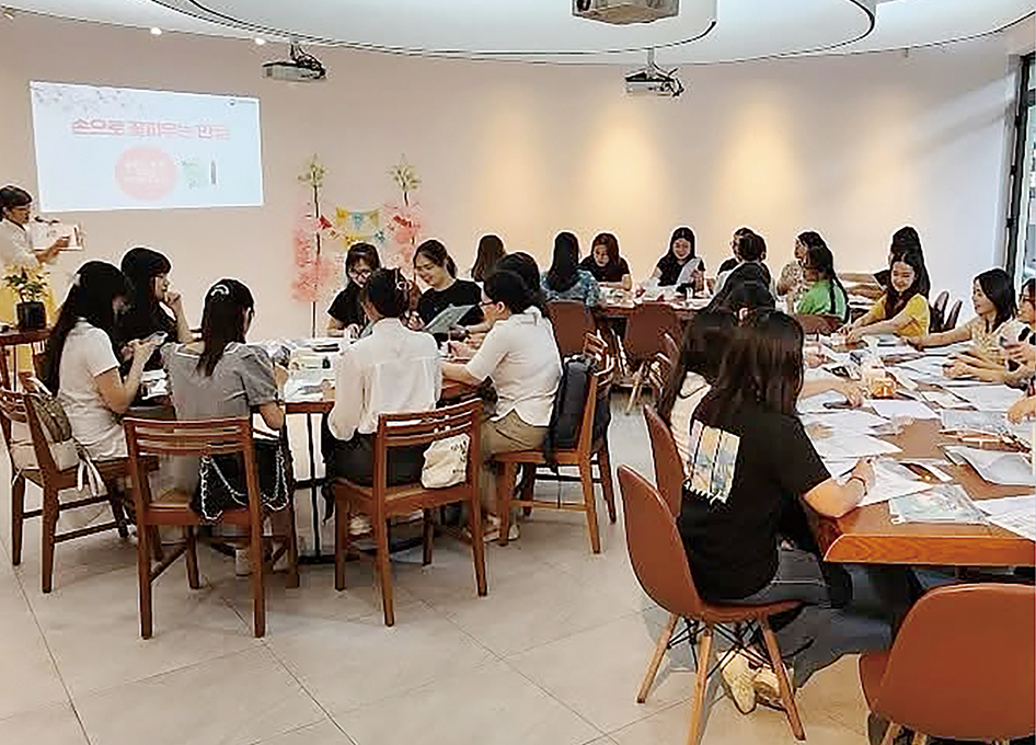‘한글실험프로젝트-근대한글연구소’ 베트남 순회전 및 연계 교육 현장 사진이다. 여러 참가자가 테이블에 둘러앉아 한글을 활용한 교육 프로그램에 참여하고 있다.